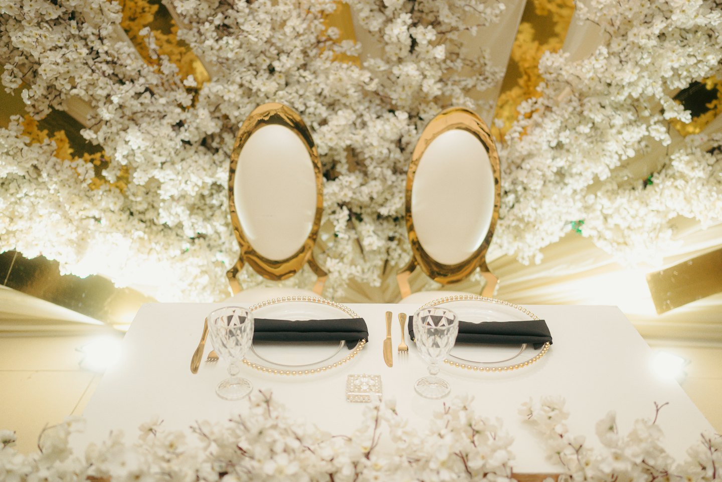 Eleganter Tisch für zwei Personen mit Goldakzenten und Kirschblüten.