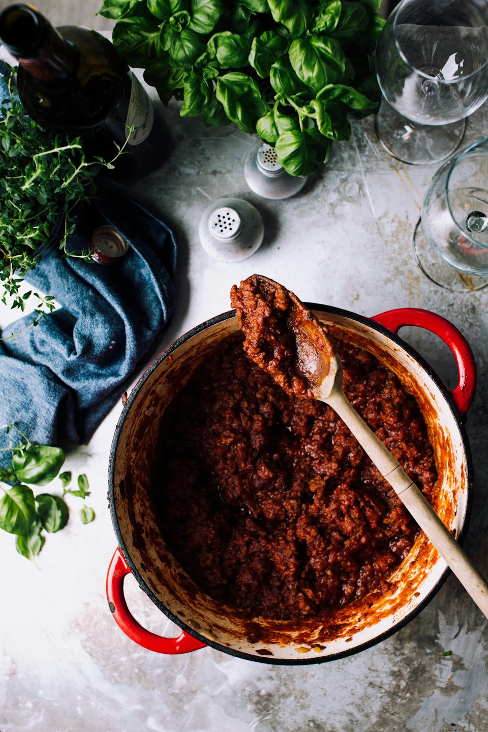 Bolognese-Soße köchelt in einem gusseisernen Topf mit einem Löffel.