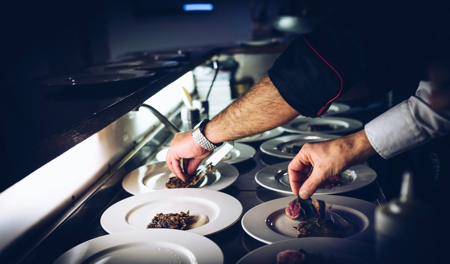 Koch richtet sorgfältig Gourmetgerichte in einer Großküche an.